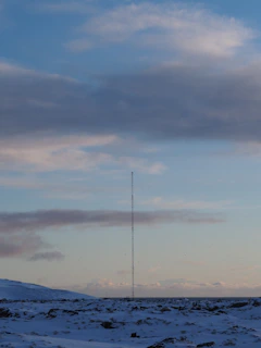 A rugged handheld radio glowing softly against a snowy Northern New York backdrop at dusk.