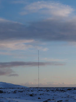 A rugged handheld radio glowing softly against a snowy Northern New York backdrop at dusk.
