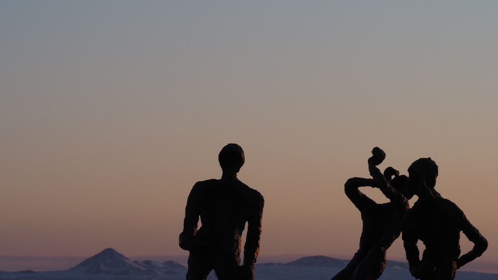 silhouette d’homme et de femme debout sur la formation rocheuse pendant le coucher du soleil