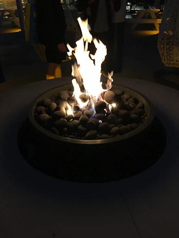 A warm, glowing fire pit surrounded by rustic wooden tables set for an intimate dinner.
