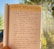 A notebook page with handwritten daily affirmations is being held up against a background of sunlight and blurred trees.