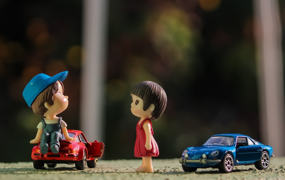 boy in red shirt and blue hat holding red car toy