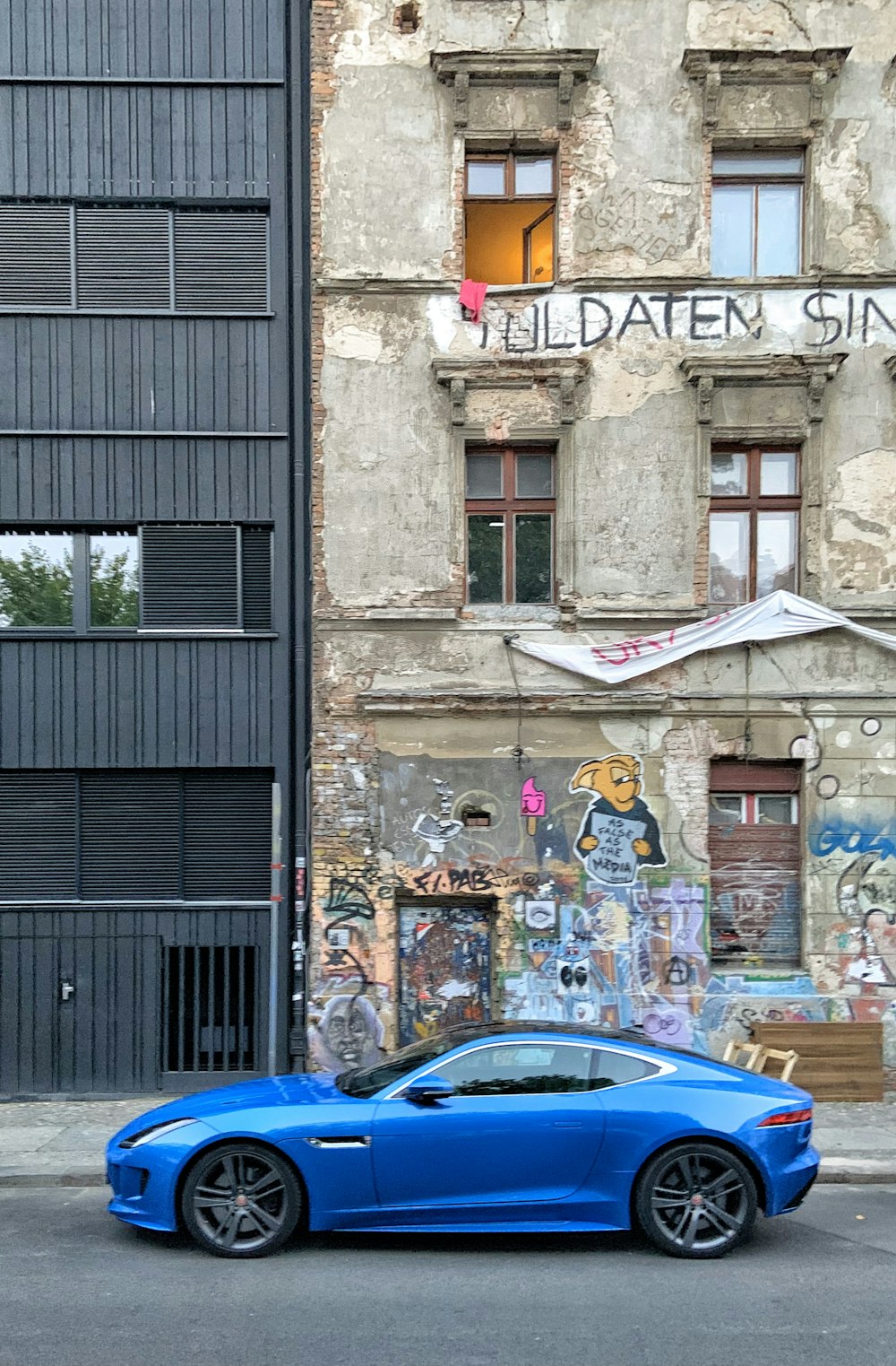 blue car parked beside gray concrete building during daytime