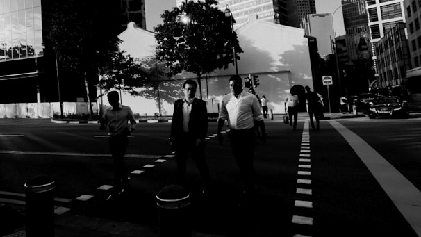 Black and white still from a film showing contrasting light and shadow on a city street.