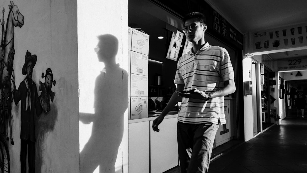 man in stripe polo shirt and pants standing beside wall