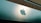 A large, reflective building facade featuring a prominent and shiny apple logo. The facade is composed of smooth, metallic panels with a modern architectural style. The upper portion of the building consists of a more textured, darker material that contrasts with the sleek panels below.