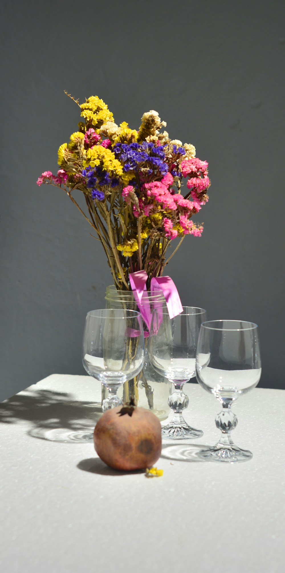 flores púrpuras y amarillas en jarrón de vidrio transparente sobre mesa blanca