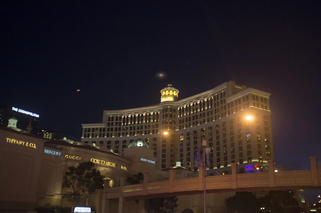 A stunning nighttime exterior view of Shiva Éclat hotel illuminated with warm golden lights against a dark sky.
