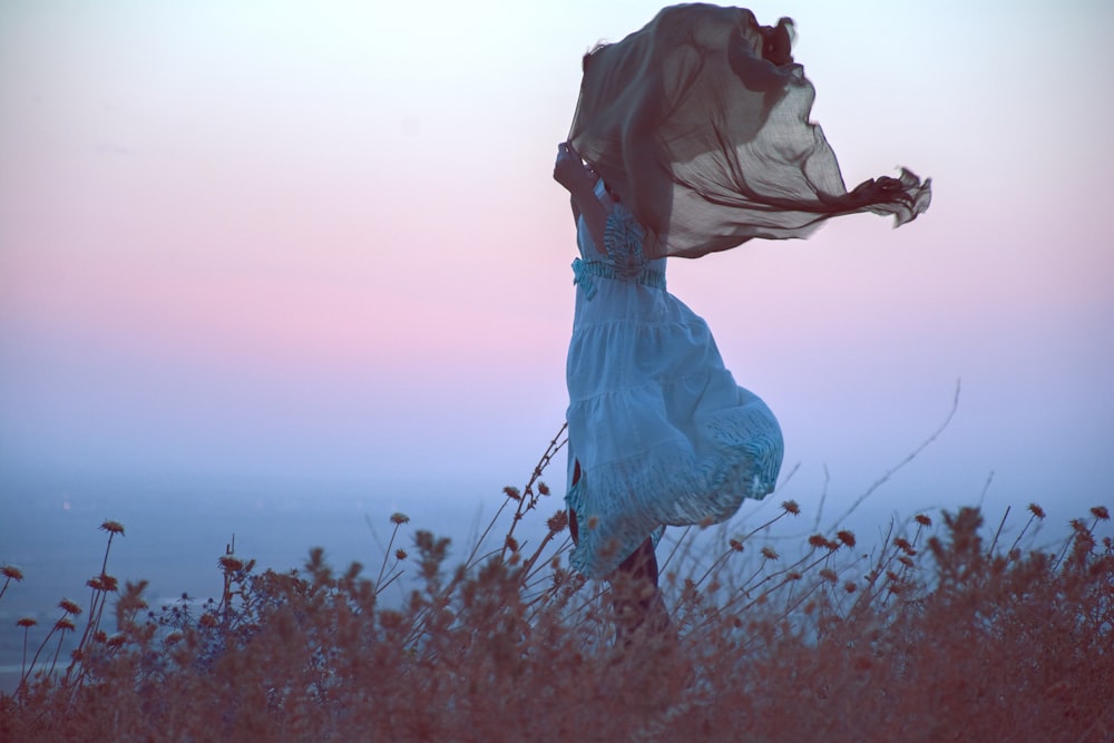 woman in white dress standing on brown grass field during daytime