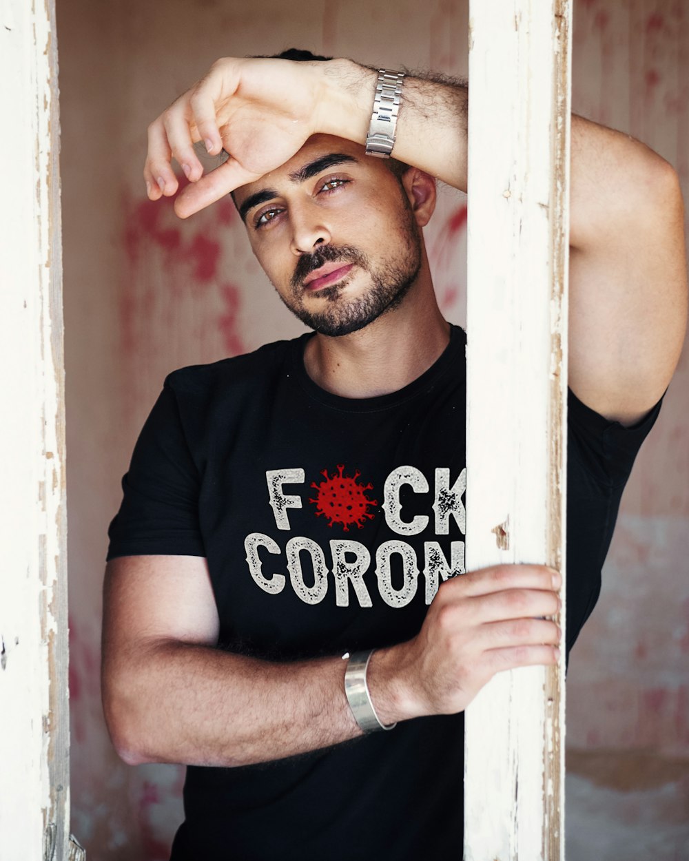 man in black crew neck t-shirt leaning on white wooden post