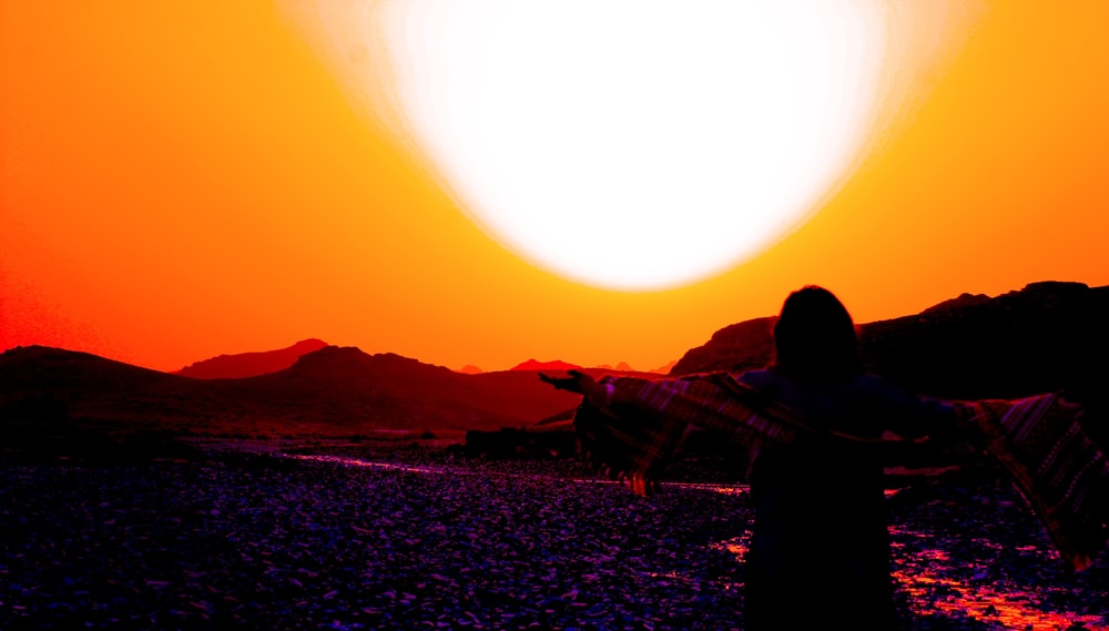 silhouette of man and woman standing on field during sunset