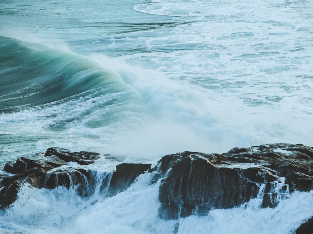 ocean waves crashing on rocky shore during daytime