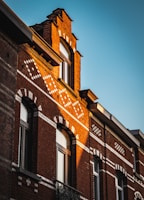 The detailed brickwork facade of a renovated commercial storefront glowing warmly in the afternoon sun.