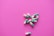 Several green and white capsules are scattered on a vibrant pink background. The capsules are positioned in a loose cluster, displaying their bold colors against the contrasting surface.