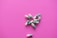 Several green and white capsules are scattered on a vibrant pink background. The capsules are positioned in a loose cluster, displaying their bold colors against the contrasting surface.