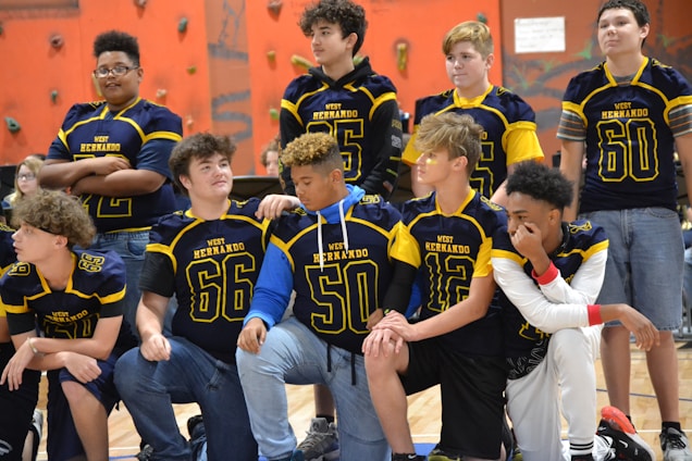 A group of Fort Collins High School wrestlers huddled together on the mat, showing team spirit.