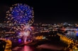 Fireworks display over a cityscape at dusk
