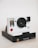 A modern instant camera with a white and black design. It features a large, circular lens and a prominent red shutter button on the front. The Polaroid branding is visible at the base, with colorful stripes below the name. The camera is angled slightly, showing the side and top.
