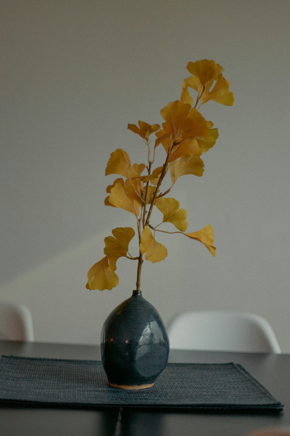 Gelbe Blätter auf blauer Glasvase