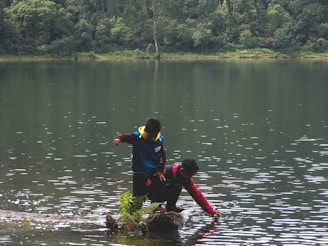 Children laughing and playing near a calm lake, their reflections shimmering on the water’s surface.