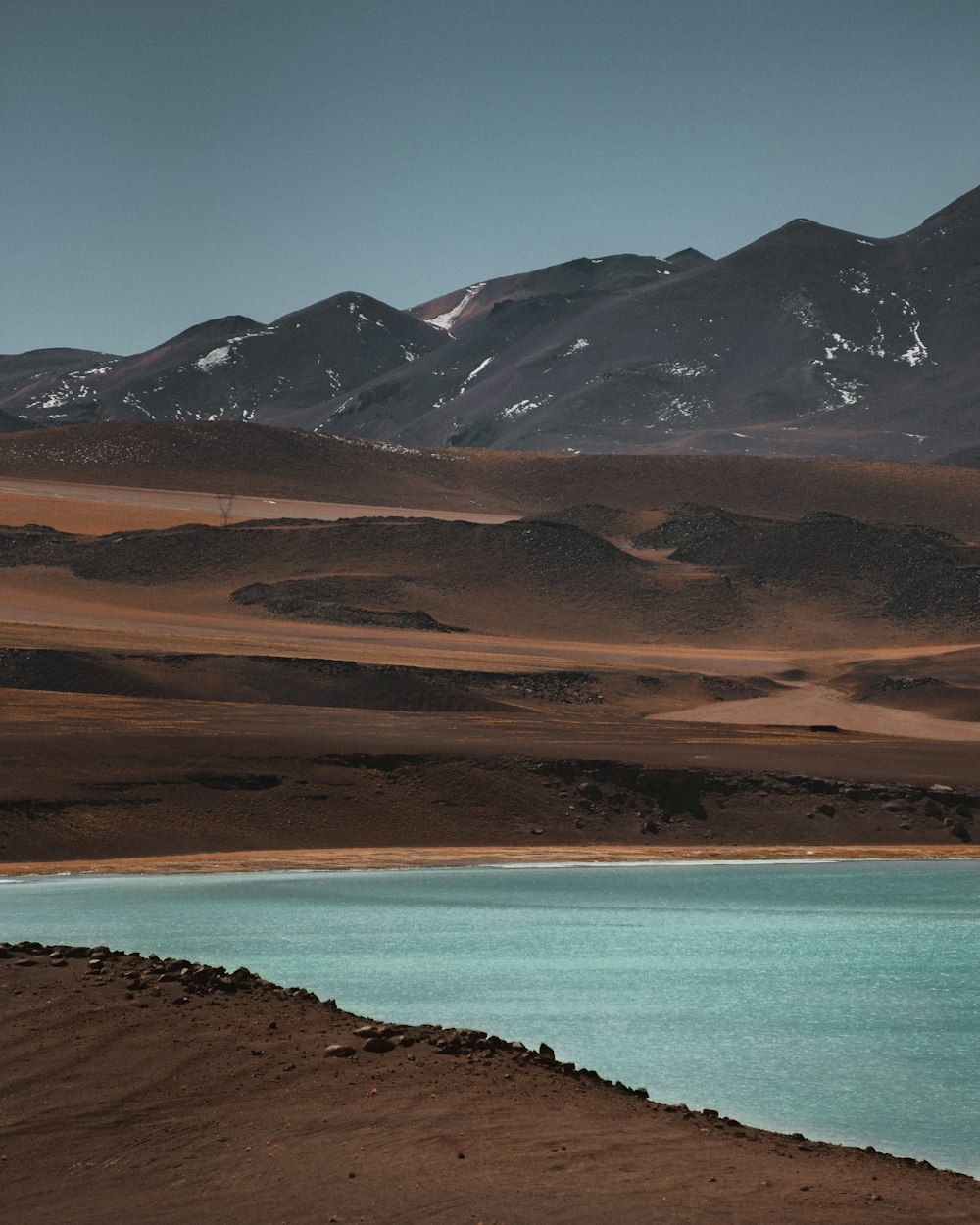 Montañas marrones y grises junto al mar azul durante el día