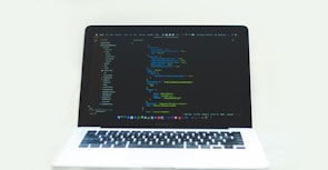A modern laptop displaying lines of code with a dark theme background.