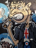 A graffiti-style artwork depicting a cartoonish character with exaggerated facial features. The character has droopy eyes, large ears, and is holding a cigarette emitting smoke. The character is wearing a jacket and a t-shirt featuring the Union Jack flag. The background includes abstract elements and vibrant colors.