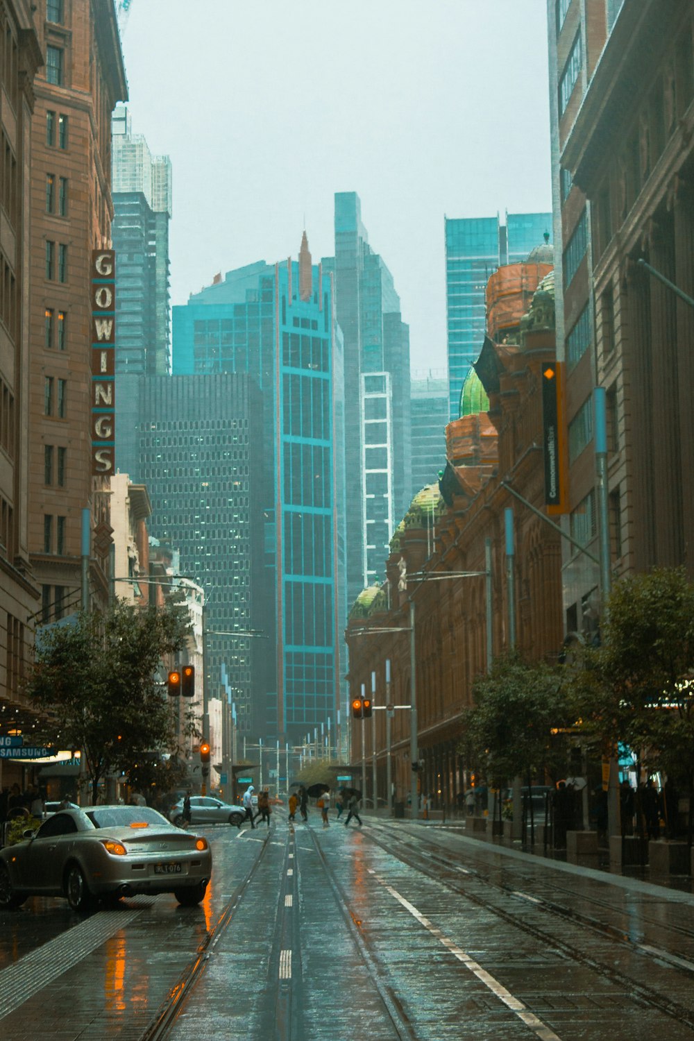 cars on road between high rise buildings during daytime