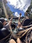 A happy couple enjoying a road trip in a convertible car with the top down on a sunny day.