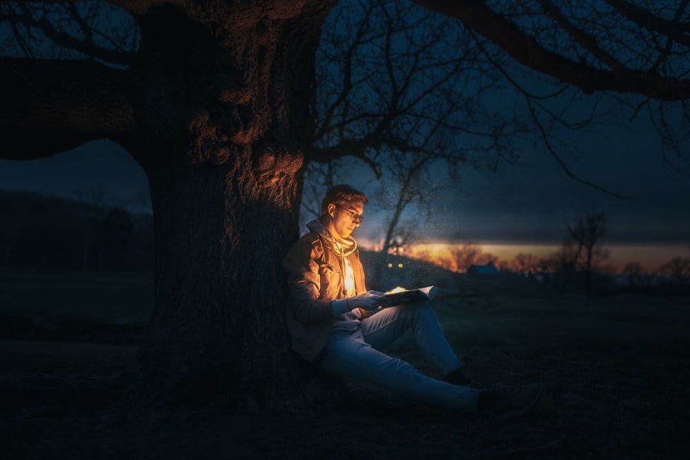 woman in white dress sitting on ground under tree during night time