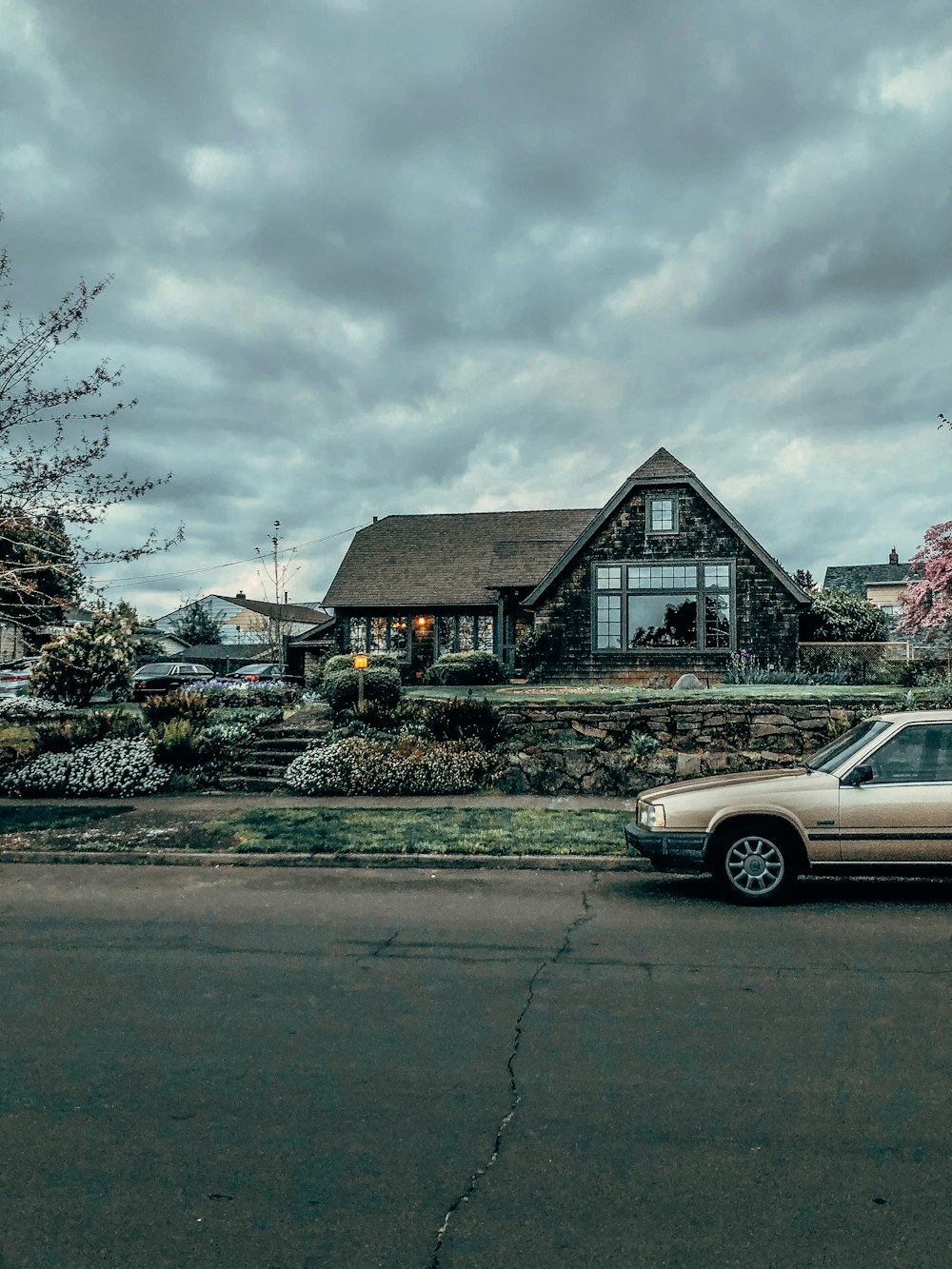 white sedan parked beside brown wooden house under white clouds during daytime