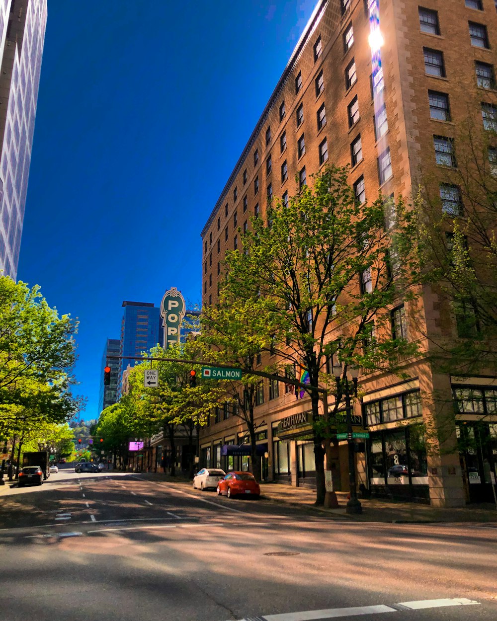 cars parked on side of the road near high rise buildings during daytime