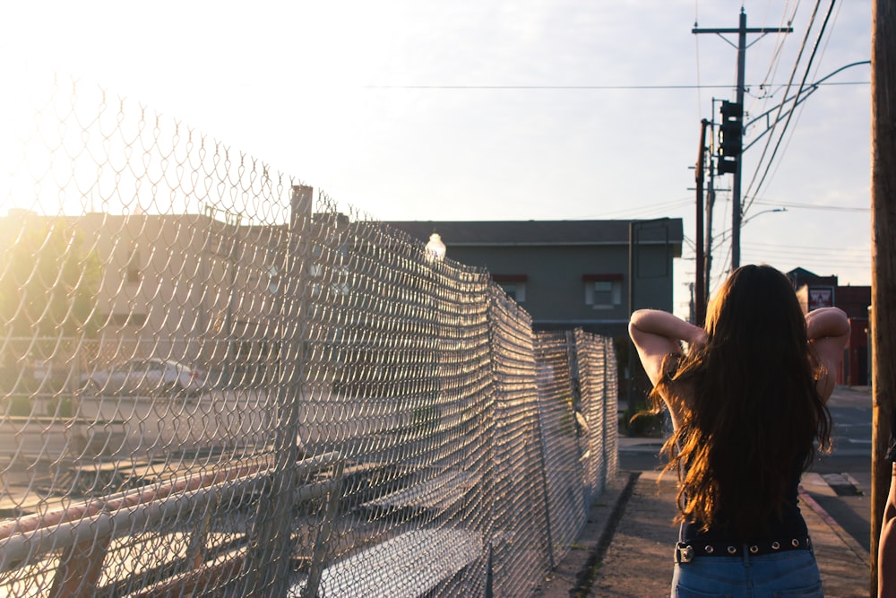 woman in black t-shirt standing beside gray metal fence during daytime