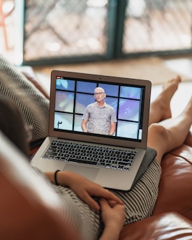 A person watching a streaming video course on a tablet at a cozy home desk.