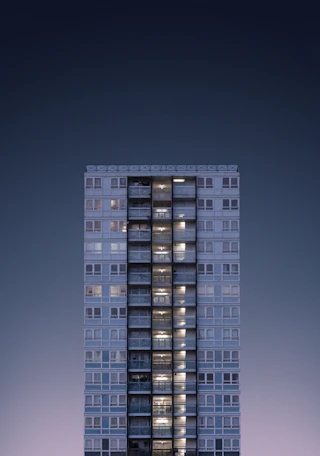 A striking nighttime photo of a minimalist building with sharp lines and illuminated windows against a dark sky