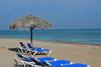 A cozy beach club setting with lounge chairs and umbrellas under a clear blue sky.