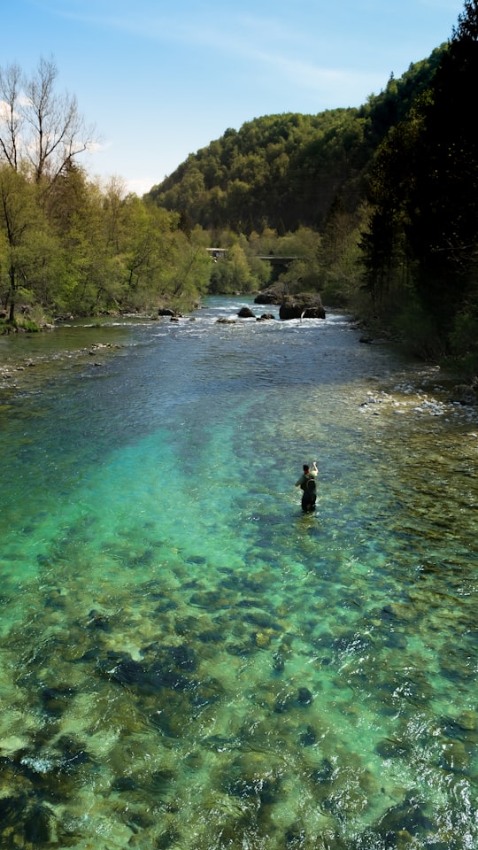 person in black jacket standing on river during daytime in Bohinjska Bela Slovenia