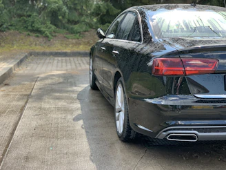 Sleek black car with water droplets beading off after graphene coating treatment.