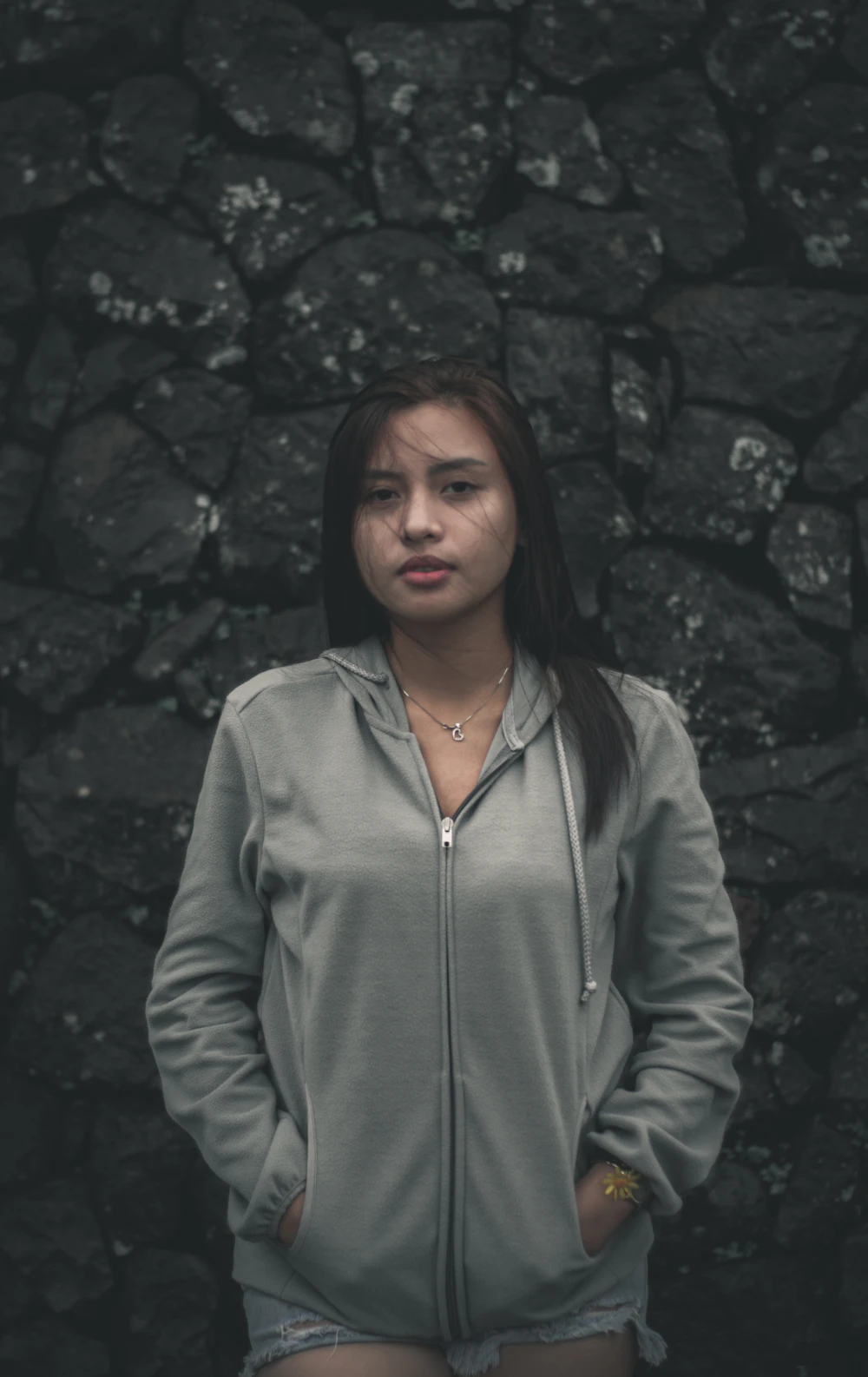 Grey zip-up hoodie against a stone wall