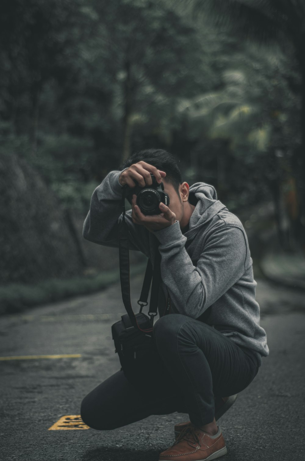 man in gray hoodie and gray pants sitting on black dslr camera