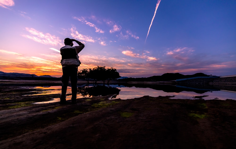 silhouette of woman standing on wooden dock during sunset