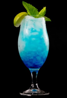 blue liquid in clear drinking glass with sliced lemon