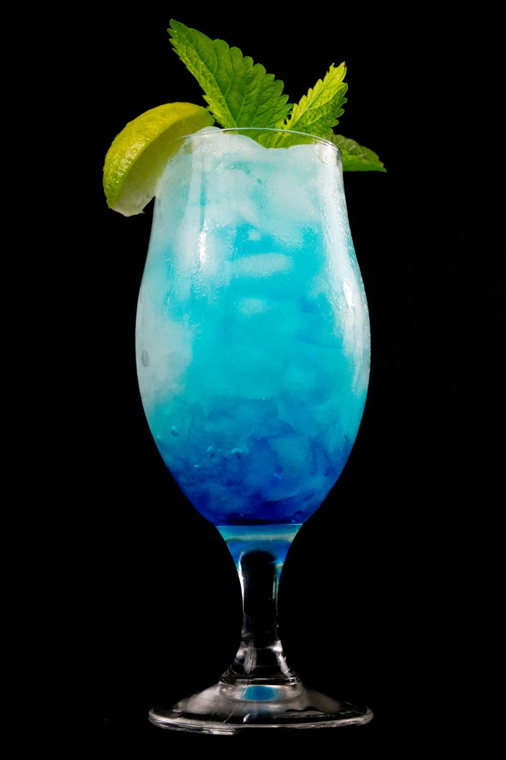 blaue Flüssigkeit im klaren Trinkglas mit geschnittener Zitrone