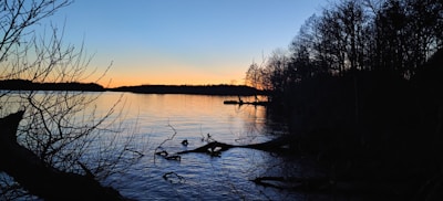 A serene lake at dusk reflecting the subtle colors of the fading light and surrounding trees.