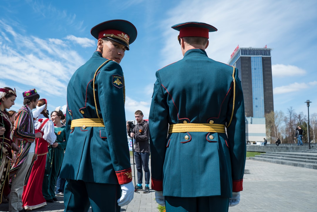 3 men in green coat standing on white floor during daytime