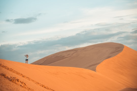 person standing on brown sand under white clouds during daytime in Mui Ne Vietnam