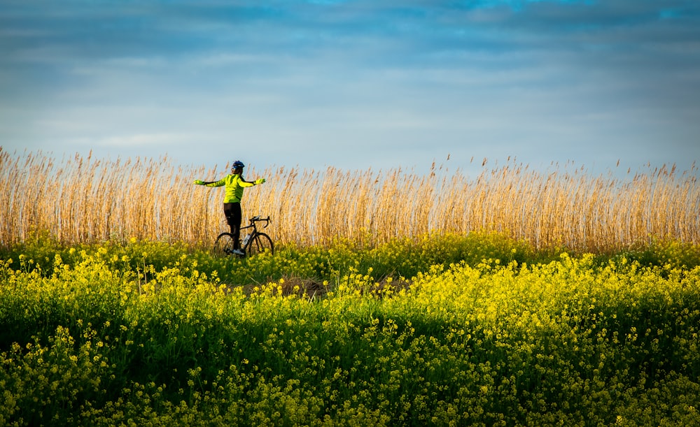 man riding bicycle on yellow flower field during daytime
