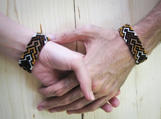 Hands gently holding a polished koa wood bracelet with visible rich grain patterns.