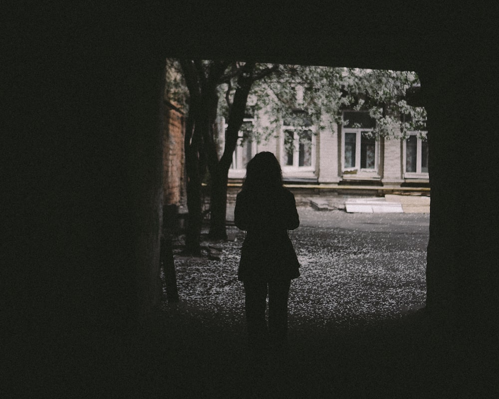 person in black coat standing in front of white building