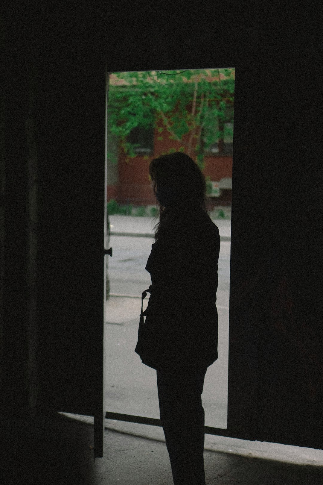 woman in black coat standing near window
